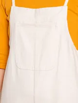 Mono de jean color crudo, de corte holgado, con pierna ancha y largo cropped. Tiene tirantes finos y un bolsillo cuadrado en el pecho.