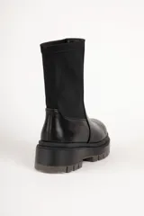 Bota corta negra de símil cuero, con punta redonda, laterales elastizados y suela tipo tractor de 5 cm de alto.