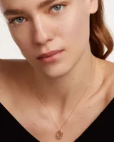 Collar de plata con baño de oro de 18k, con una cadena de eslabones y un dije circular pavimentado con circonias multicolor y una barra central con la letra I.