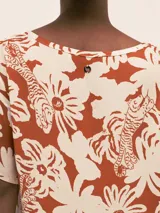 Vestido largo camisero de seda viscosa con estampado de flores y tigres en tonos naranja y blanco. Cuenta con botones nacarados, bolsillos, lazo para la cintura y aberturas laterales.