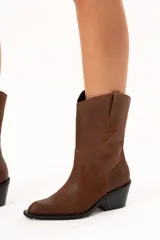 Bota de caña media con diseño estilo western, confeccionada en cuero con acabado texturado craquelado. Presenta tiradores laterales, puntera redondeada y taco cuadrado de altura media.