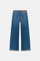 Jeans de tiro alto con corte culotte y pernera ancha. Presenta bolsillos de plastrón en el frente con detalle de pespuntes decorativos en forma de onda y costuras verticales a lo largo de la pierna. Cierre frontal con cremallera y botón metálico.