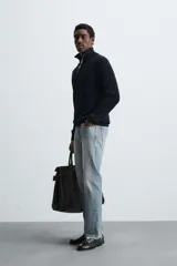 Jersey de punto perlado con cuello perkins y cierre frontal de cremallera. Presenta un corte regular fit, manga larga y acabados en rib en puños y bajo.