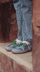Zapatillas urbanas de cuero celeste y mesh gris, con suela de goma y doble juego de cordones intercambiables en color verde y blanco.