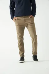 Pantalón chino color beige, de corte slim, con bolsillos laterales y traseros. Se ajusta a la cintura con cinturón de cuero marrón.