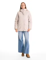 Campera 3 en 1 de color beige, con sistema de capas desmontables. La capa exterior es de tejido técnico resistente al viento y lluvia ligera, con capucha fija, cierre frontal con solapa, bolsillos de parche y ajuste elástico interno en la cintura. Incluye una campera interior capitoneada ultraliviana que puede usarse de forma independiente.