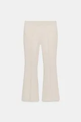 Pantalón de vestir color beige claro, tiro medio, con corte flare (campana) en el bajo. Presenta bolsillos laterales y falsos bolsillos de vivo en la espalda.