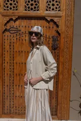 Camisa de lino negra con bordados dorados en forma de árbol o palmera estilizada. Presenta cuello camisero, botones frontales dorados y pliegues verticales en la parte inferior delantera.