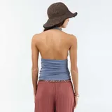 Top gris con cuello halter y escote en V pronunciado. Presenta frunces en el busto y en los laterales, aportando textura y un ajuste ceñido al cuerpo.