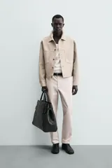 Pantalón chino de corte regular fit, confeccionado en tejido de algodón con elasticidad. Presenta bolsillos frontales, bolsillos traseros de vivo y cierre frontal con cremallera y botón.