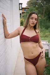 Conjunto de bikini color bordó, compuesto por un corpiño halter con breteles para atar y una bombacha colaless.