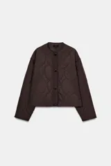 Cazadora corta acolchada de color marrón oscuro, con cuello redondo, manga larga y cierre frontal con botones. Presenta un diseño de costuras acolchadas con patrón geométrico y bolsillos delanteros de vivo.