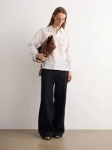 Camisa blanca de manga larga con detalles bordados y calados geométricos, cuello camisero y cierre frontal de botones.