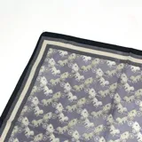 Pañuelo cuadrado de tela liviana, con estampado de carruajes antiguos en tonos gris y crema, y bordes en contraste negro.