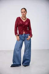 Blusa de encaje color bordó, de manga larga, con escote en V y volados en el borde delantero.
