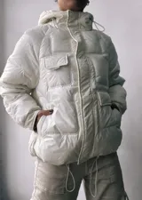 Campera puffer blanca con capucha, cierre frontal con cremallera y bolsillos con solapa en el pecho.