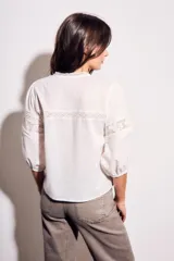 Blusa negra de algodón peinado con calce oversize, escote en V, mangas tres cuartos abullonadas y detalles de encaje y bordados en el frente y mangas.