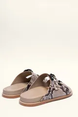 Sandalias de cuero color negro con dos tiras anchas sobre el empeine, cada una con hebillas metálicas ajustables y detalles de tachas plateadas. La suela es de cuero con un borde de color madera.