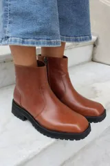 Bota corta de cuero azul con suela track negra, detalle de tira con hebilla metálica y tachas decorativas en el tobillo.