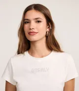 Remera de algodón color blanco tiza, de corte ajustado al cuerpo, cuello redondo y manga corta. Presenta la palabra "GNARLY" estampada en el centro del pecho con apliques de strass plateados.