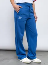 Pantalón de jogging recto en color azul, confeccionado en felpa. Presenta cintura elástica con cordón de ajuste, bolsillos laterales y detalles de la marca Umbro y el escudo del Club Nacional de Football bordados en la parte frontal.
