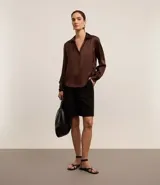Camisa de satén color verde lima, con cuello inglés, cierre frontal con botones y mangas largas con puños abotonados. Presenta un acabado brillante y fluido.