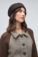 Campera corta con cuerpo de lana tejida en textura tweed y mangas de punto liso en color marrón. Presenta cuello camisero, cierre frontal con botones y bolsillos frontales tipo plaque.