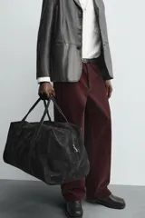 Pantalón de hombre color bordó oscuro, de corte ancho (wide fit), confeccionado en tejido de algodón con acabado flocada o efecto aterciopelado. Presenta cinco bolsillos y cierre frontal con cremallera y botón.