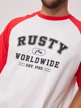 Remera blanca con mangas raglán negras y estampado frontal con el logo de Rusty en azul.