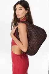 Bolso tipo hobo de cuero marrón oscuro, con diseño trenzado y asa integrada al hombro.