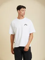 Remera blanca de manga corta con cuello redondo y un pequeño logo estampado en el pecho izquierdo.