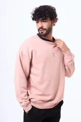 Buzo de felpa color rosado con cuello redondo, mangas largas y logo bordado en el pecho.