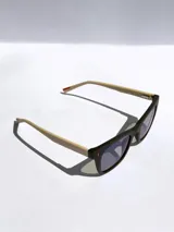 Lentes de sol con armazón bicolor, frente negro y patillas en tono beige con detalle de marca grabado. Cuentan con cristales polarizados con protección UV 400.