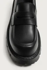 Mocasín negro de estilo casual, con detalle de antifaz en el empeine, horma redonda y suela gruesa track con volumen.