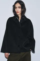 Chaqueta de corte recto confeccionada en mezcla de lana, color negro. Presenta cuello solapa, manga larga y cierre frontal con botones a tono.