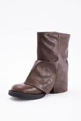 Botas de caña media confeccionadas en cuero vegano color negro, con diseño de solapa frontal y detalle de hebilla metálica en la parte superior.