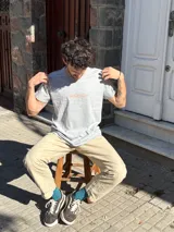 Remera blanca de manga corta con cuello redondo y un pequeño logo estampado en el pecho.