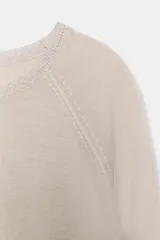 Jersey de punto color marrón topo, de manga larga y corte recto, con cuello redondo ribeteado con hilo brillante.