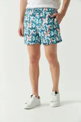 Short de baño con estampado botánico en tonos turquesa, blanco y azul. Presenta cintura elástica con cordón ajustable, dos bolsillos laterales y uno trasero, además de un logo bordado en la pierna.