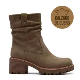 Bota de caña media confeccionada en cuero, con diseño de efecto arrugado en la parte superior y detalle de tira con botón a presión. Cuenta con taco cuadrado de altura media y suela track dentada.