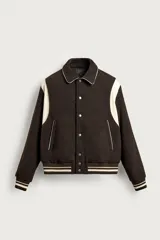 Cazadora bomber estilo varsity de corte cropped, color marrón oscuro con mangas y detalles en tono tostado. Cuenta con cuello de solapa, bolsillos de vivo en la cadera, acabados en rib y cierre frontal con botones a presión.