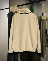 Buzo de pana color beige con cuello polo, cierre frontal parcial y forro interior de corderito. Presenta diseño oversized, bolsillos laterales y puños elásticos.