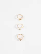 Set de tres anillos dorados de diferentes diseños: uno liso con forma de espiral, uno con forma de "V" y uno con una bolita decorativa.
