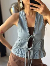 Chaleco de jean celeste con escote en V y lazos frontales.