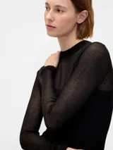 Buzo de tejido fino y semitransparente con cuello redondo y mangas largas, diseñado con una capa superpuesta estilo musculosa de punto acanalado.