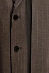 Blazer oversize de Zara con diseño a rayas verticales, cuello con solapa de muesca y hombreras. Presenta un cierre frontal cruzado con doble botonadura, bolsillos delanteros con solapa y un bolsillo de vivo en el pecho. Incluye forro interior a tono.