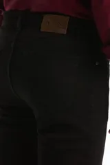 Pantalón de jean negro de corte slim fit, con diseño clásico de cinco bolsillos, presillas para cinturón y cierre frontal con botón y cremallera.