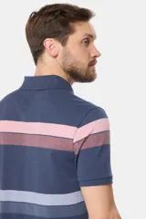 Remera polo de piqué con rayas horizontales en beige, verde, azul y gris. Cuello y puños en azul. Logo bordado en el pecho.