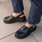 Sueco de cuero vacuno color marrón con estampado de cocodrilo, suela de goma negra y hebilla metálica plateada.