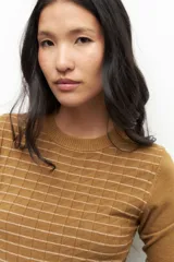 Sweater color ocre con diseño tramado a cuadros, de manga larga y cuello redondo.